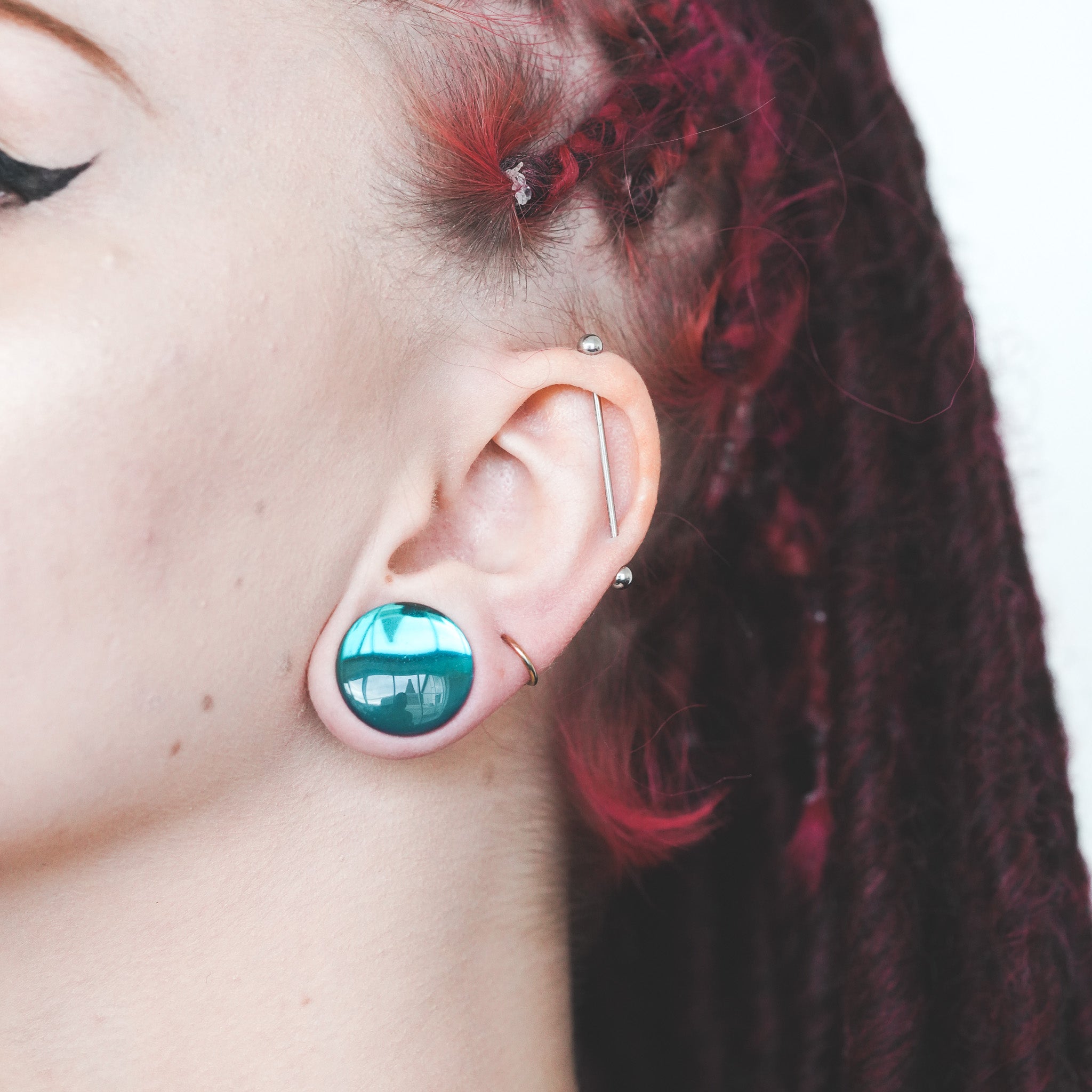 close up black aurora plug with scaffold piercing red hair