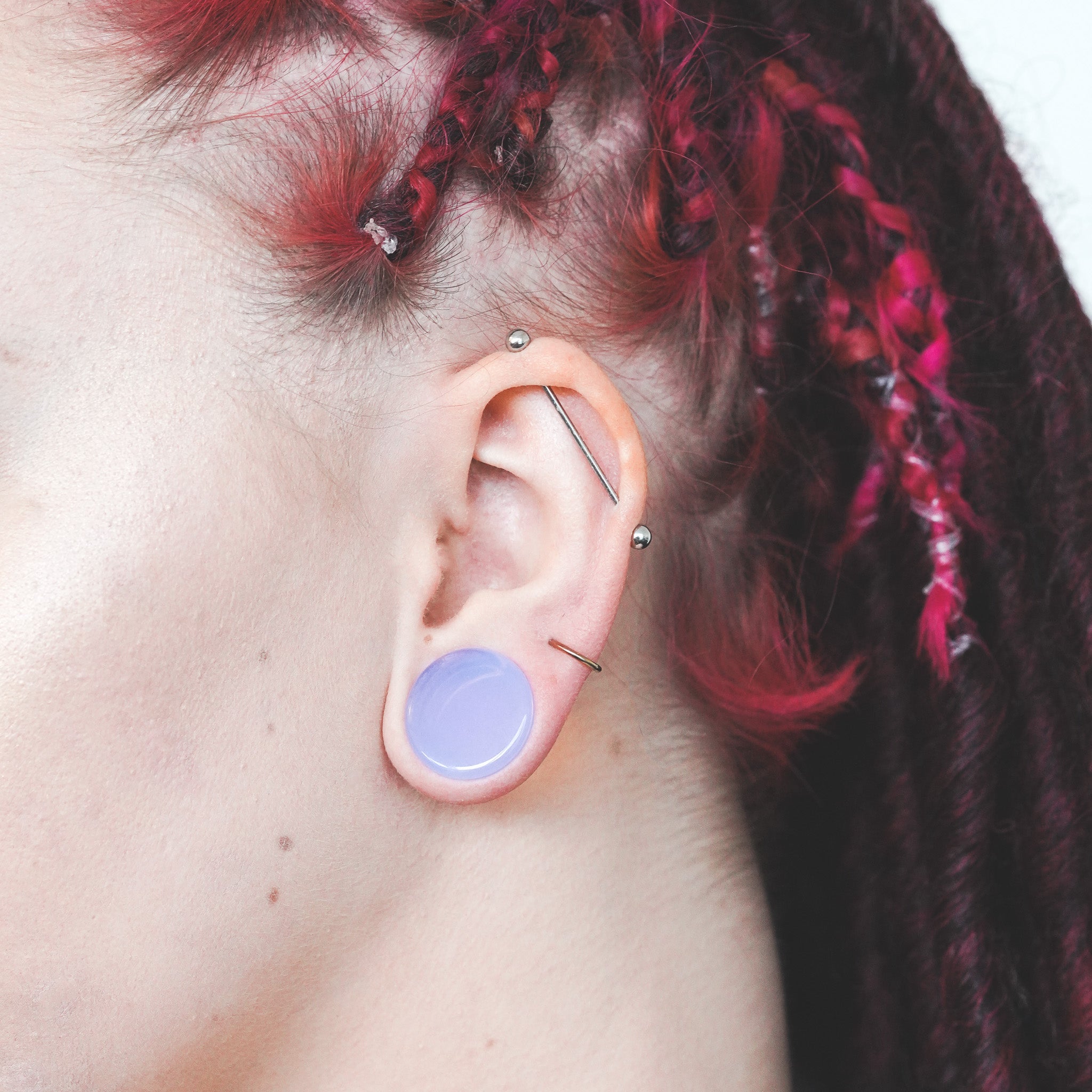 model wearing purple opalite plug in 19mm with piercings red hair