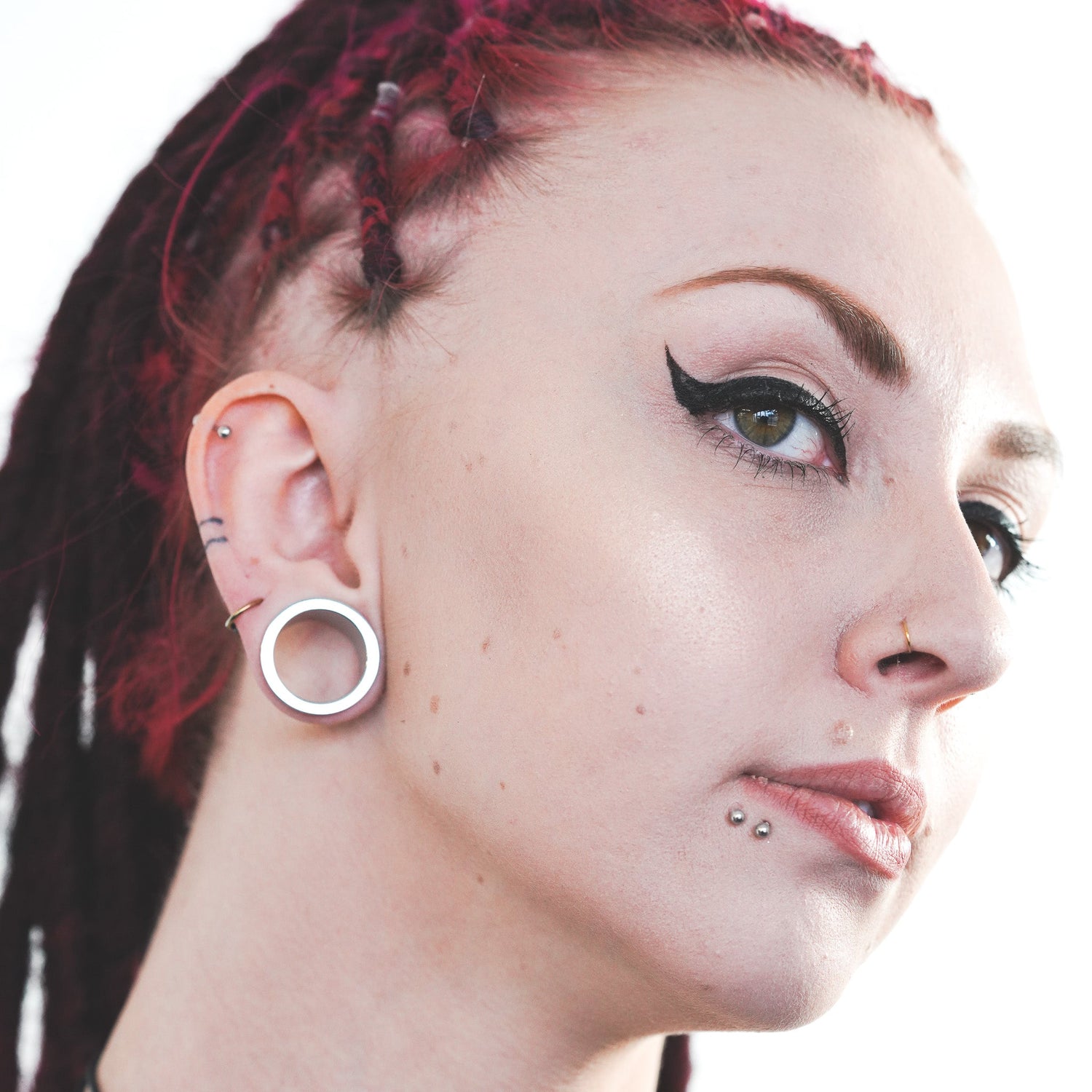 Model wearing surgical steel tunnels for stretched ears